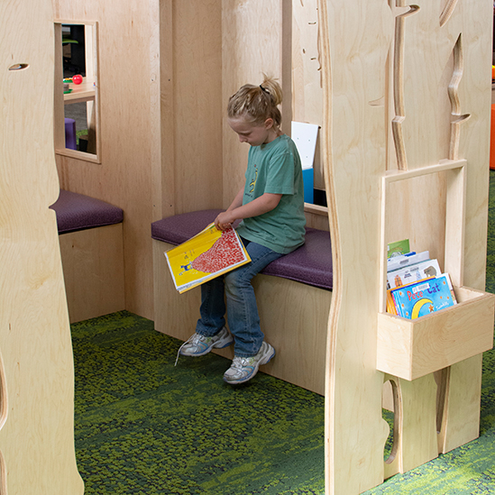 girl reading in a tree house play area